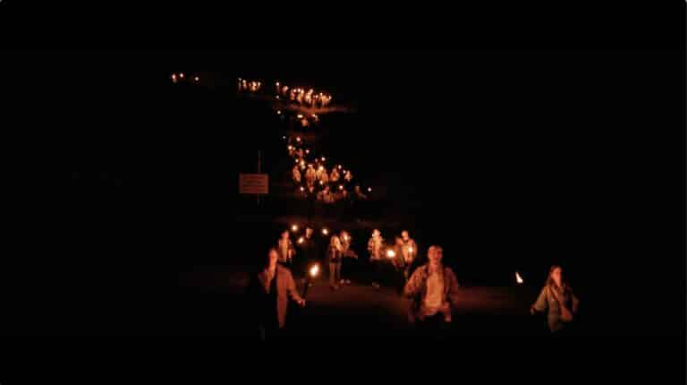 Marche de groupe vue du ciel vers fort de cavalerie avec torches de feu soir Seminaire immersif western voyage Agence evenementiel Paris WATO