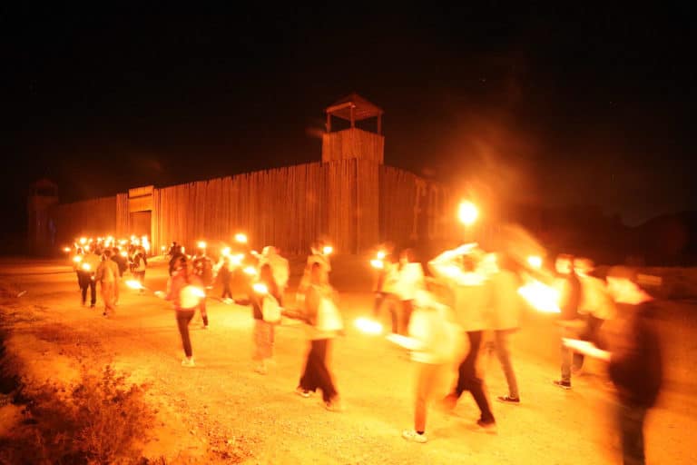 Entree de groupe mouvement dans le fort de cavalerie avec torches de feu soir Seminaire immersif western voyage Agence evenementiel Paris WATO