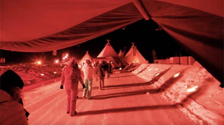 Marche de groupe de nuit sur neige vers tipis Seminaire immersif montagne voyage prive Alpe Huez Agence Evenementiel Paris WATO