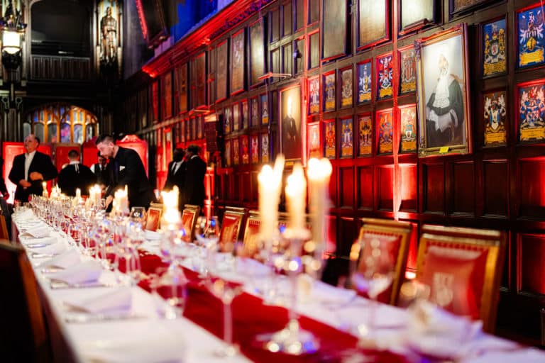 Table avec nappe rouge et chandeliers en tenue de l ordre de chevalerie de la jarretiere Soiree immersive Secret Society Chateau au coeur de Londres Voyage Prive Agence evenementiel Paris WATO