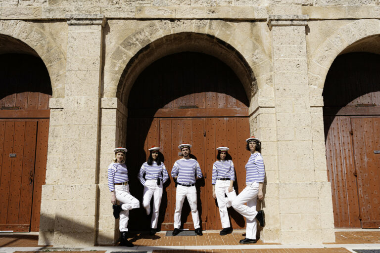 Team WATO en tenue de marins adossée à impressionante porte en bois Evenement spectaculaire Marseille Fort Ganteaume Alliance Piscines Agence Evenementiel Paris WATO